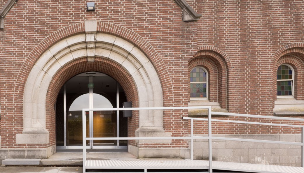 De drempelloze inkom met hellingbaan aan de voorgevel van de kerk