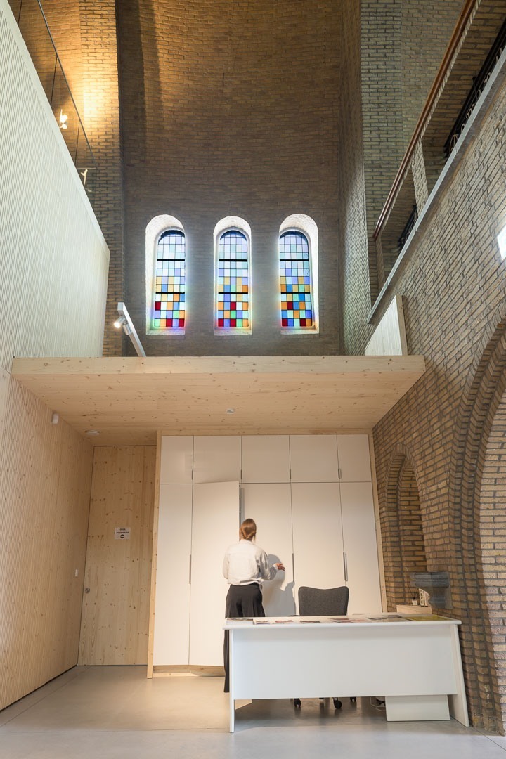 De onthaalbalie onder de glasramen van de kerk