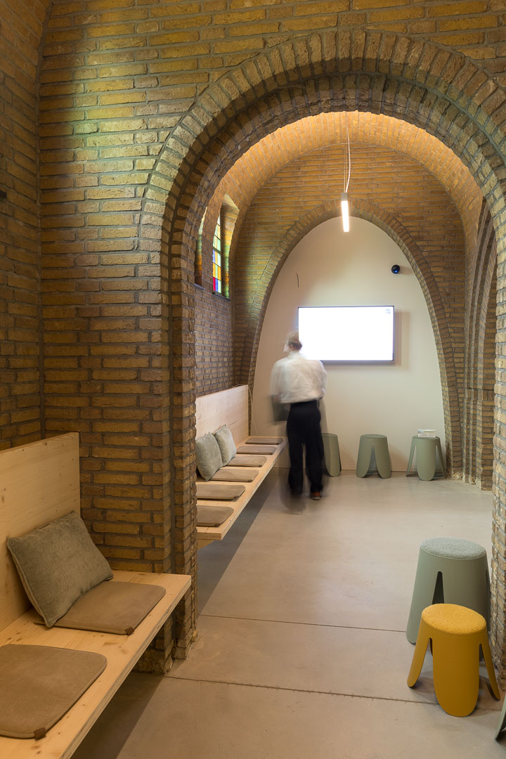 Wachtzaal in de zijbeuk met houten zitbanken onder de bakstenen bogen